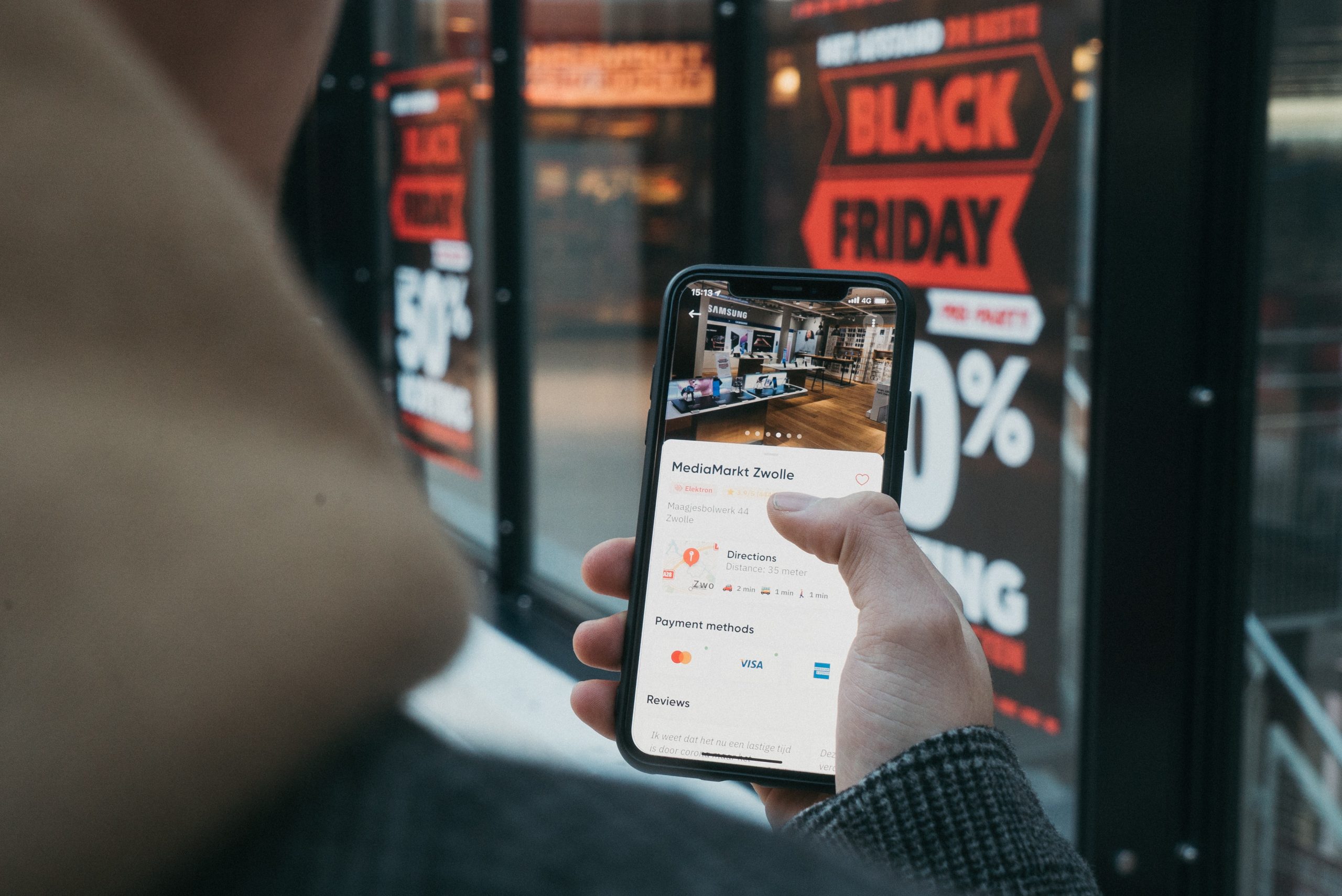 Someone using a smartphone next to a Black Friday sale poster.