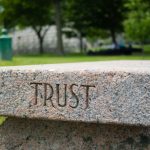 A park bench with the word 'trsut' engraved on its side.